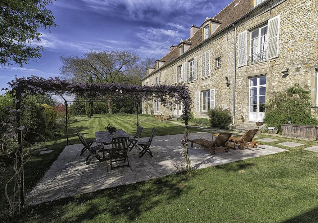 um pátio com uma mesa e cadeiras em frente a um edifício em Chambres d'hôtes de Parseval em Senlis