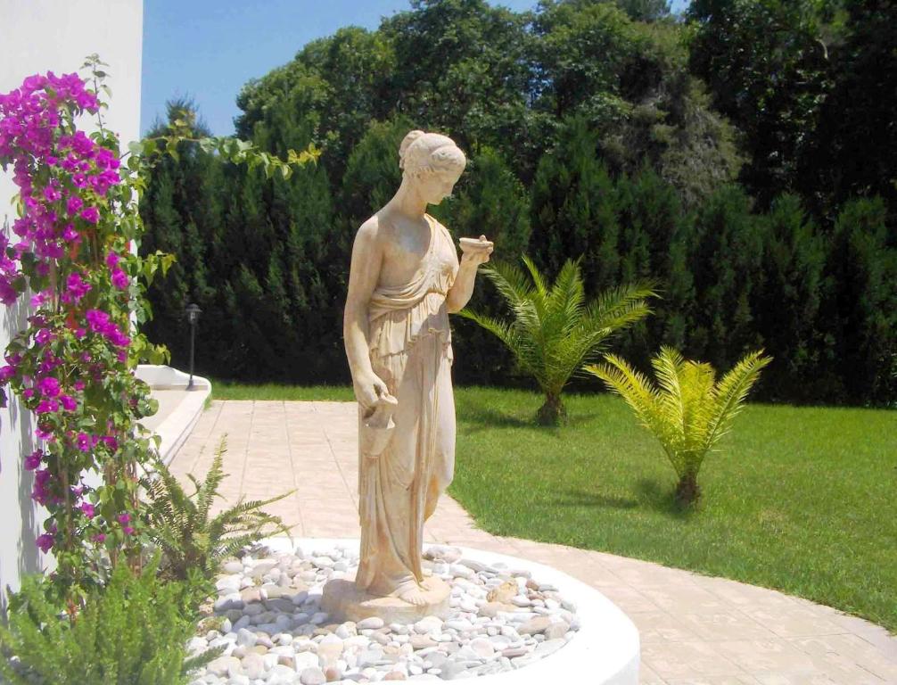 una estatua de una mujer parada en un jardín en Skiathos Driades, en Koukounaries