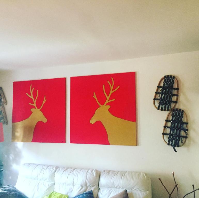zwei Gemälde von Hirschen an einer Wand über einer Couch in der Unterkunft Relax holiday in Sestriere