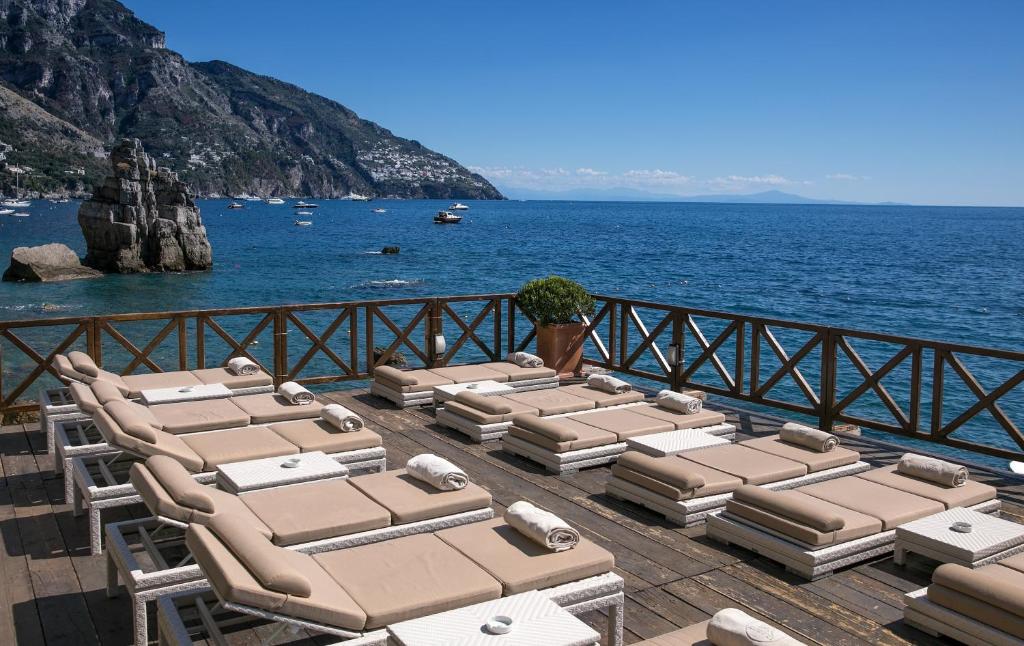 una fila di sedie a sdraio su un molo con l'oceano di Hotel Le Agavi a Positano