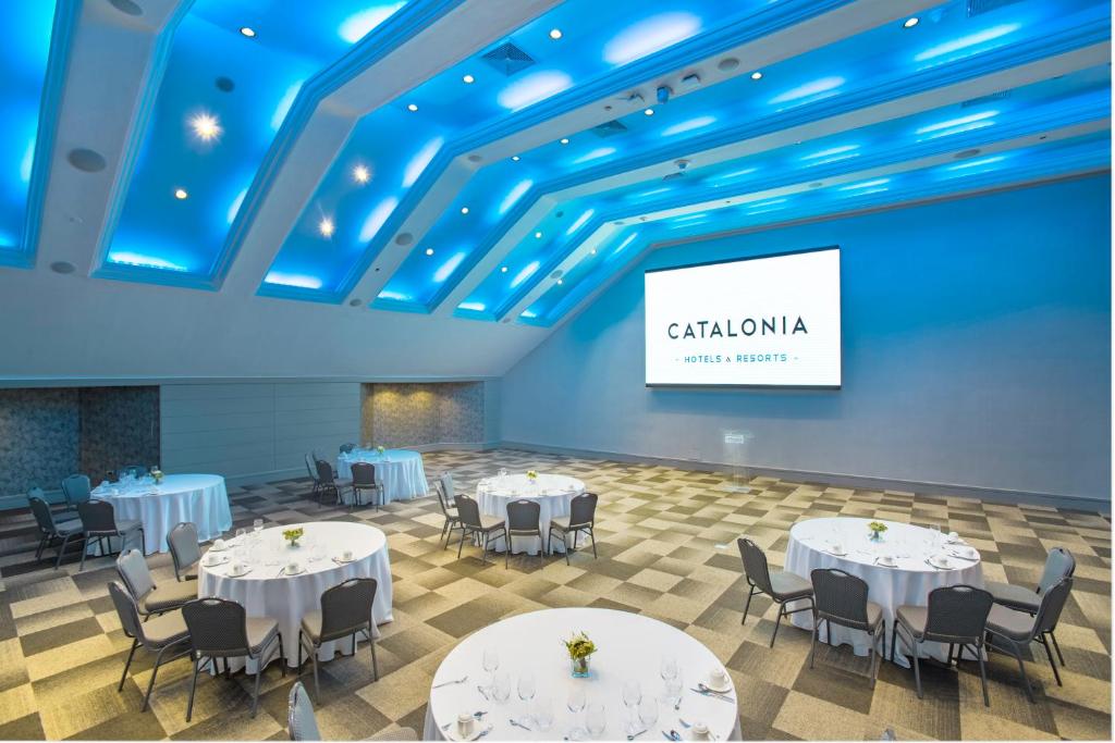 a conference room with white tables and chairs and a screen at Catalonia Santo Domingo in Santo Domingo