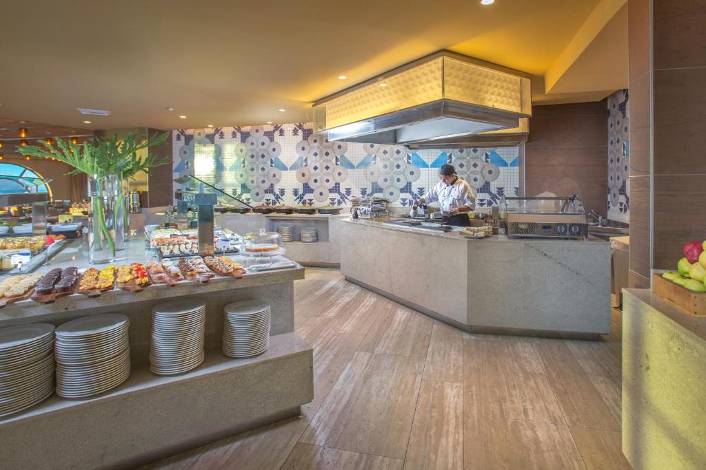 a kitchen with a chef preparing food in a restaurant at Catalonia Santo Domingo in Santo Domingo