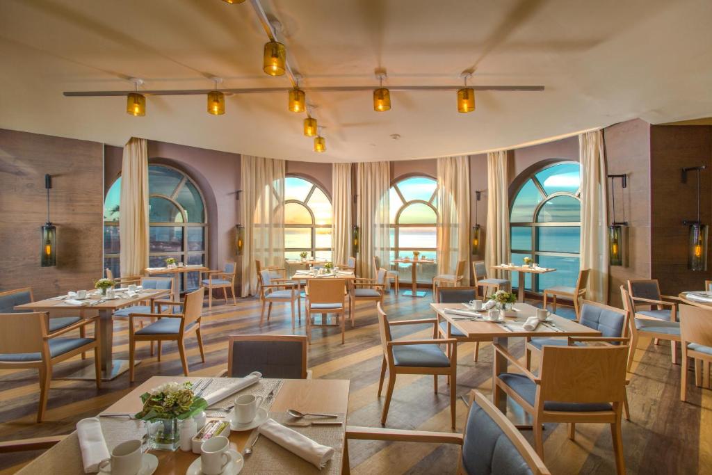 a restaurant with tables and chairs and windows at Catalonia Santo Domingo in Santo Domingo