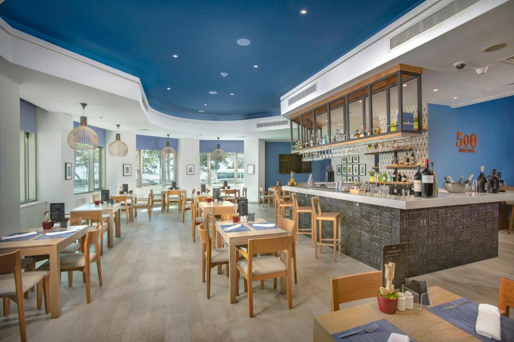a restaurant with tables and chairs and a bar at Catalonia Santo Domingo in Santo Domingo