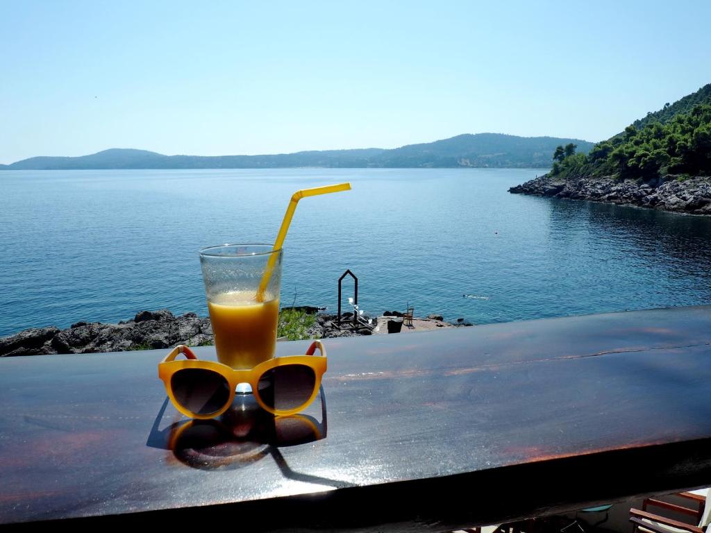 un par de gafas de sol y una bebida en una mesa cerca del agua en Paliouri House, en Paliouri