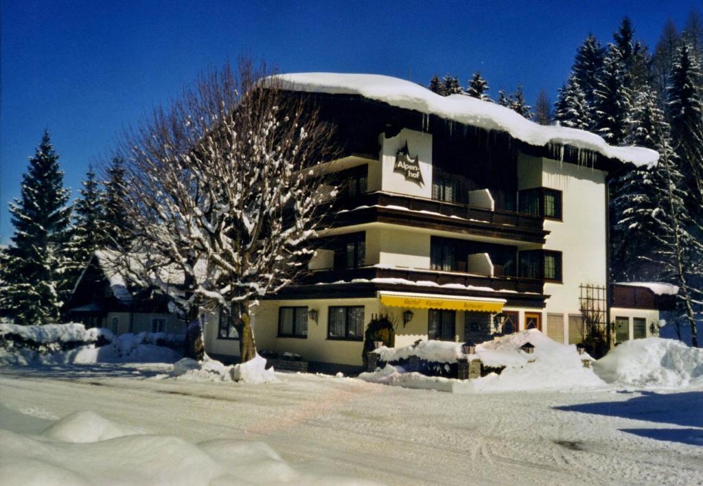 um edifício coberto de neve com uma árvore em frente em Alpenhof Annaberg em Annaberg im Lammertal