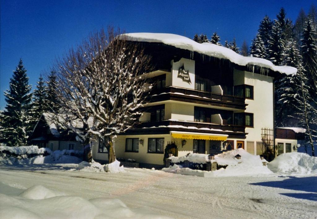 un bâtiment recouvert de neige avec un arbre devant lui dans l'établissement Alpenhof Annaberg, à Annaberg-Lungötz