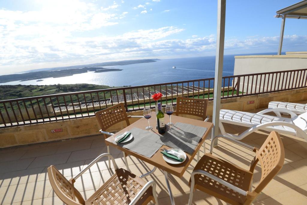 a table and chairs on a balcony with a view of the ocean at Il-Bukkett B&B in Qala