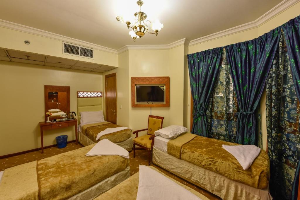 um quarto de hotel com duas camas e uma televisão em Al Mukhtara Golden em Medina
