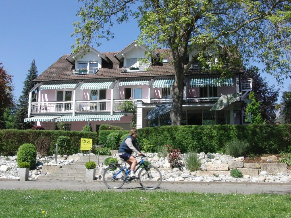 un hombre montando una bicicleta delante de una casa en Iris am See garni, en Radolfzell am Bodensee