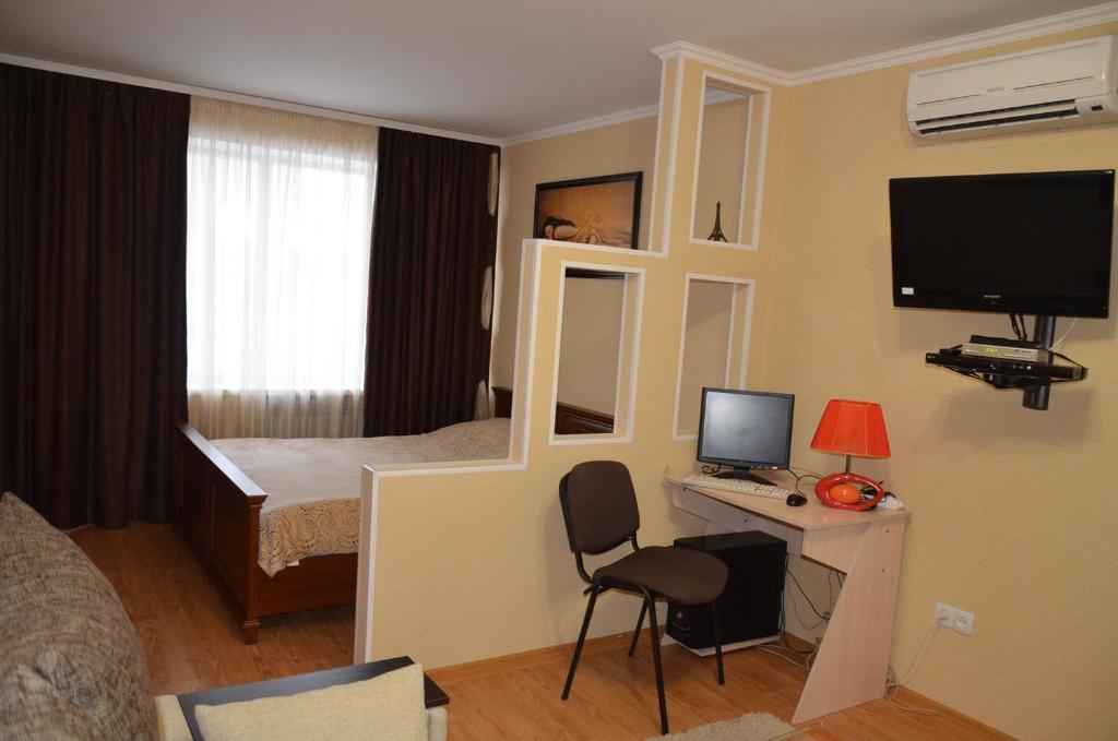 a hotel room with a bed and a desk with a computer at Apartments in the city centre of Nikolaev in Mykolaiv