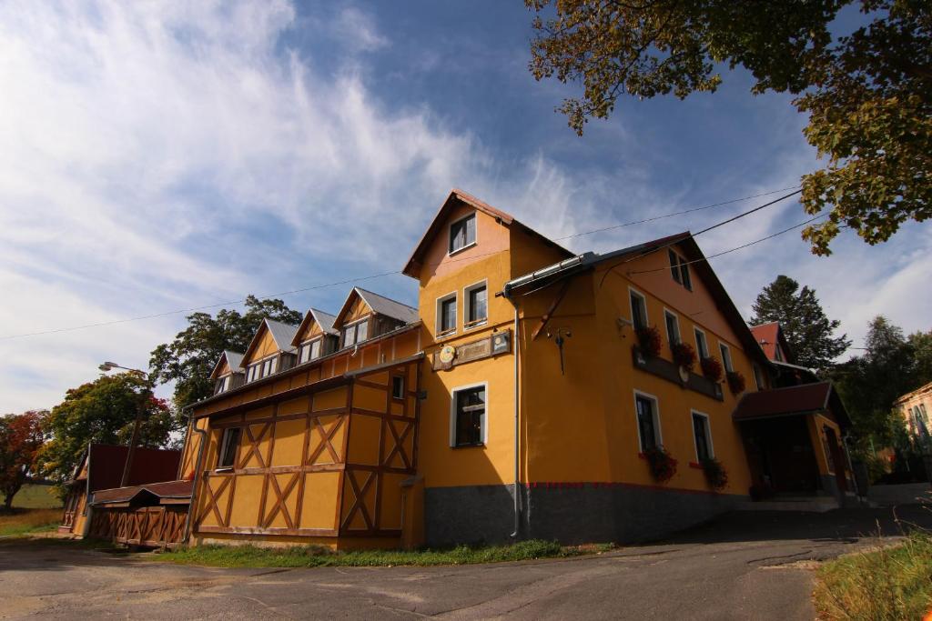 un grand bâtiment jaune assis sur le côté d'une rue dans l'établissement Hotel Restaurant Svejk, à Bublava