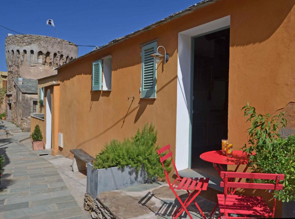 two red chairs and a table outside of a building at Latu Corsu - Côté Corse - Gites et chambres d'hôtes au Cap Corse in Ersa