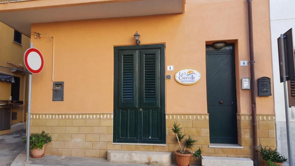 a building with a green door and twowindows at Le Tre Caravelle in Trabia