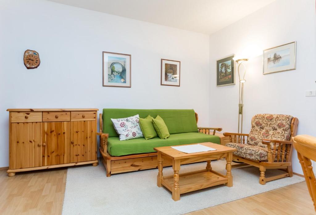 a living room with a green couch and a chair at Apartma Sončnica in Kranjska Gora