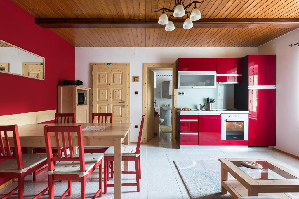 una cucina con armadi rossi, tavolo e sedie di Apartma Angelca a Kranjska Gora