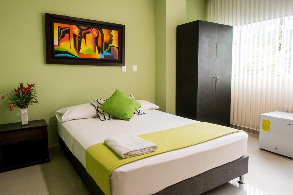 1 dormitorio con 1 cama con una pintura en la pared en Palma Real Hotel Boutique, en Acacías