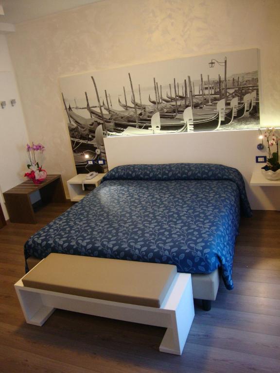 a bedroom with a bed and a painting of a boat at Hotel Venezia in Caorle