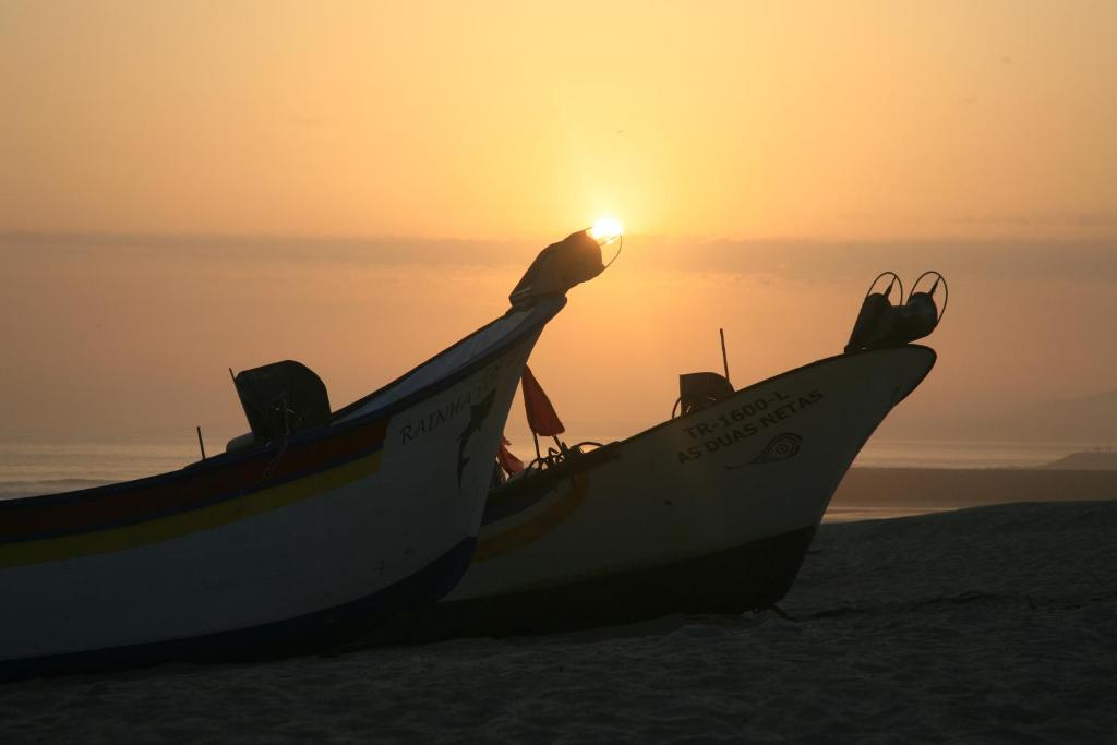 two boats sitting on the beach at sunset at Beach & Relax - Studio in Costa da Caparica