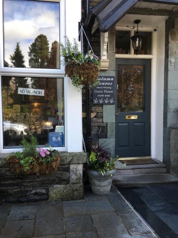 a store front with a blue door and potted plants at Autumn Leaves Guest House in Windermere