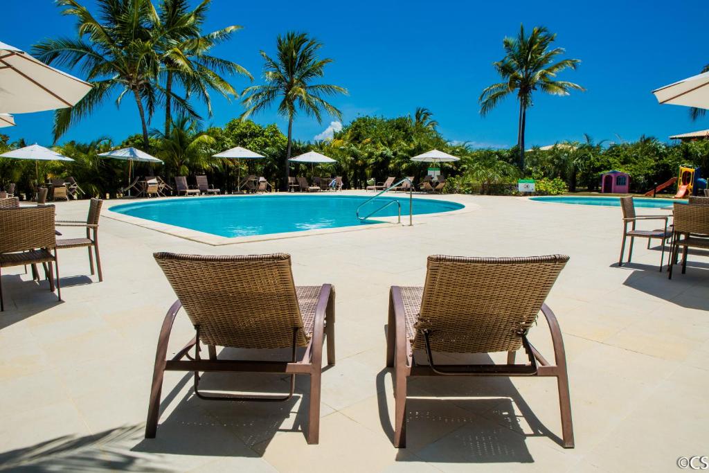een zwembad met 2 stoelen en een tafel bij Apartamento Terraco Buganvilias - Reserva Imbassai in Imbassai