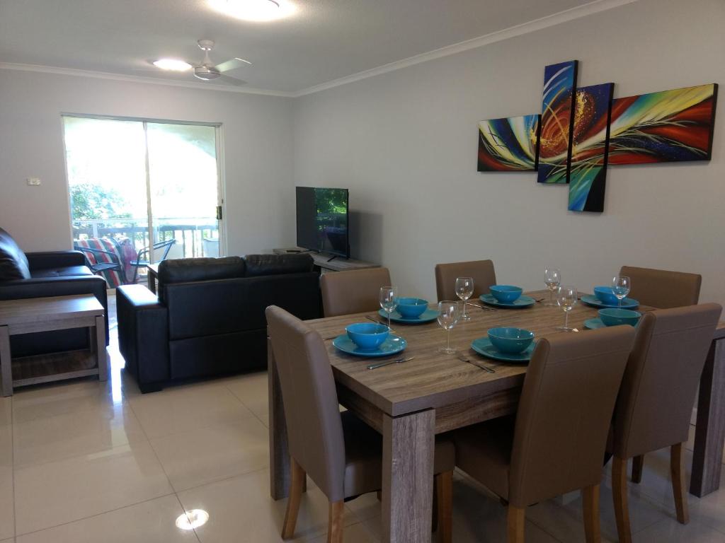 a dining room and living room with a wooden table and chairs at Oasis Private 2 Bed Apartment in Caloundra