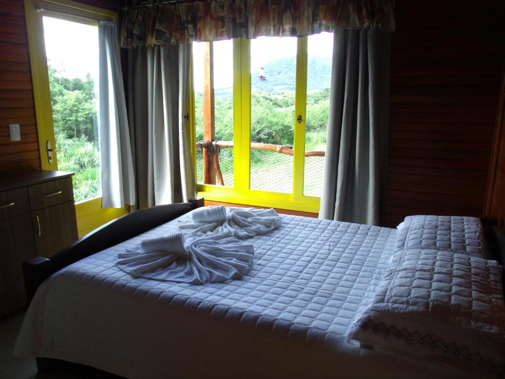 Ce lit se trouve dans une chambre dotée d'une grande fenêtre. dans l'établissement Chale dos Beija Flores, à Gramado