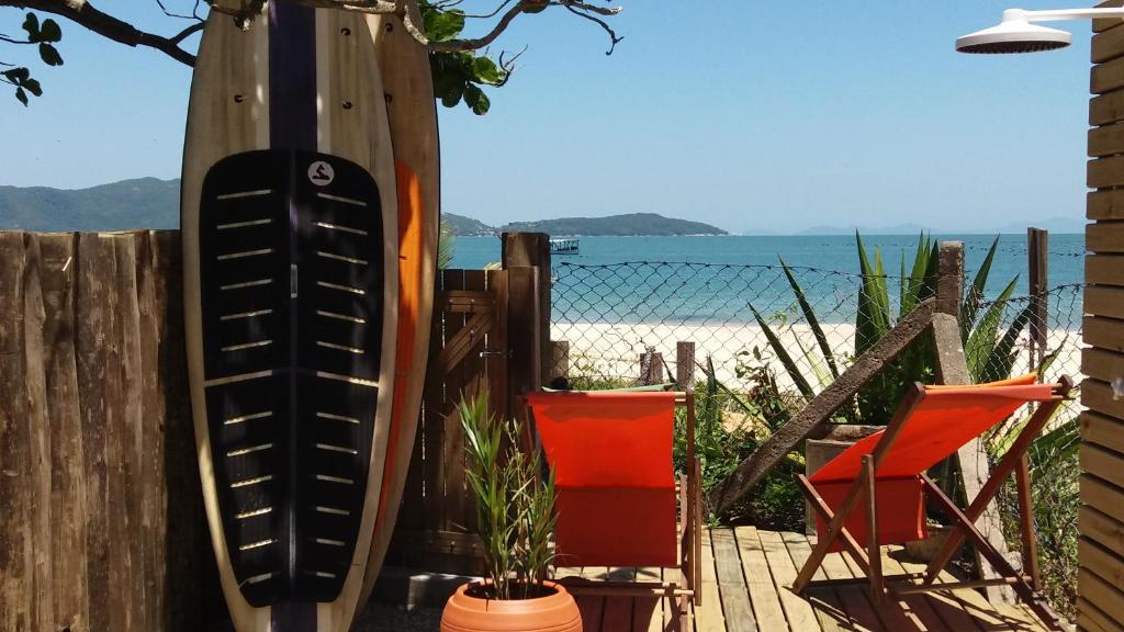 a surfboard leaning against a wooden fence next to a chair at Residencial Bombinhas Pé na Areia in Bombinhas