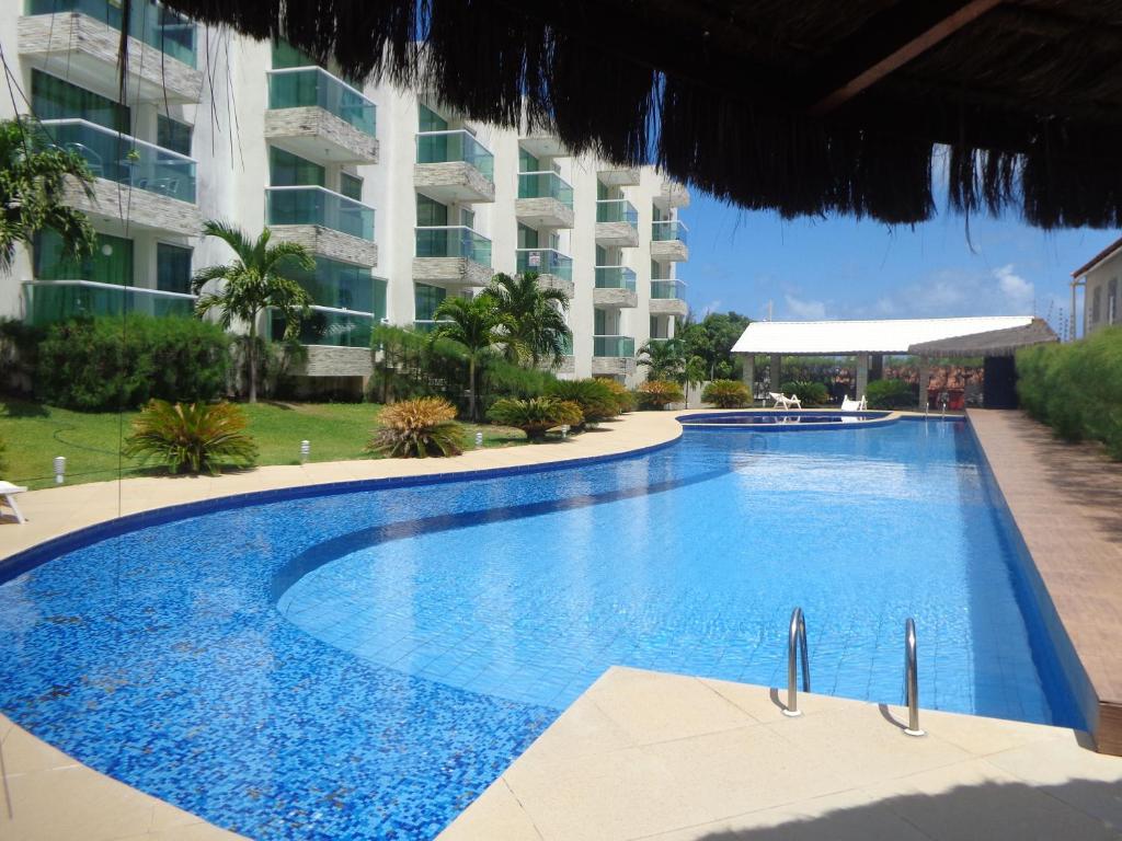 a large swimming pool in front of a building at Condomìnio Mar & Sol in Conde