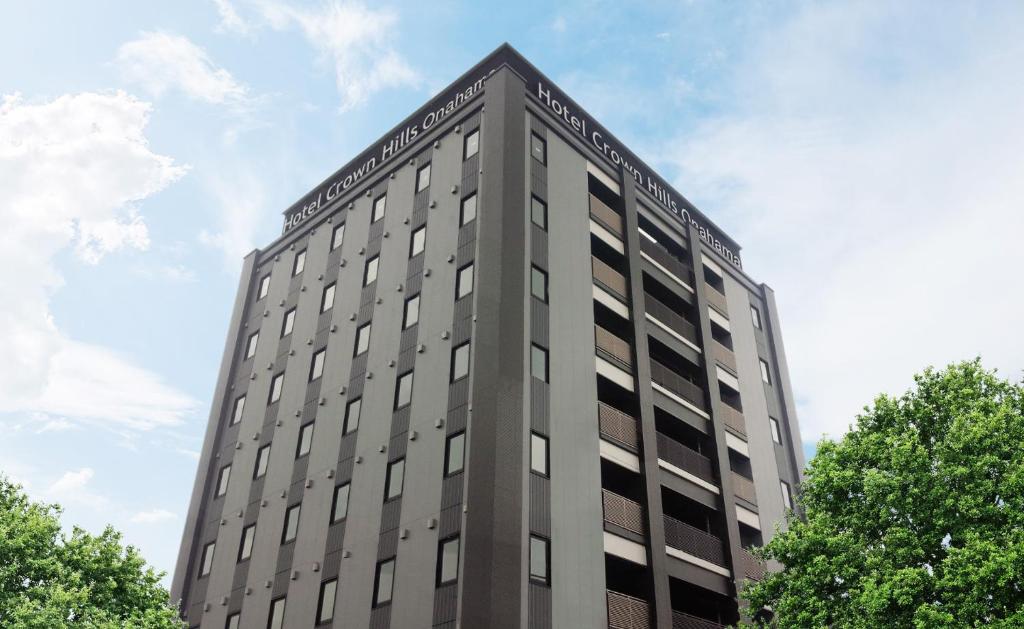 um edifício cinza alto com árvores em primeiro plano em Hotel Crown Hills Onahama em Iwaki