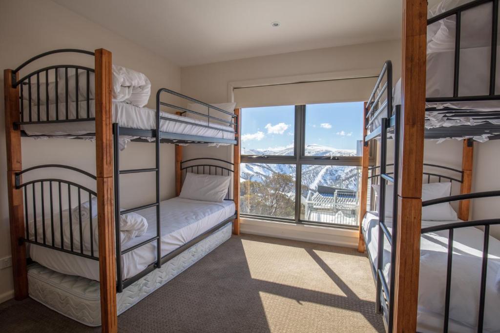 Cette chambre comprend 3 lits superposés et une fenêtre. dans l'établissement Ultima Apartments, à Mount Hotham