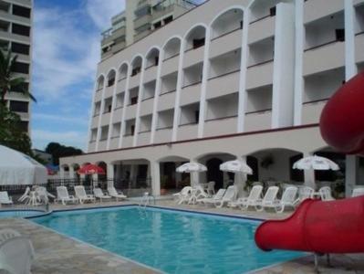 um hotel com piscina em frente a um edifício em Hotel Areia Branca em Caraguatatuba