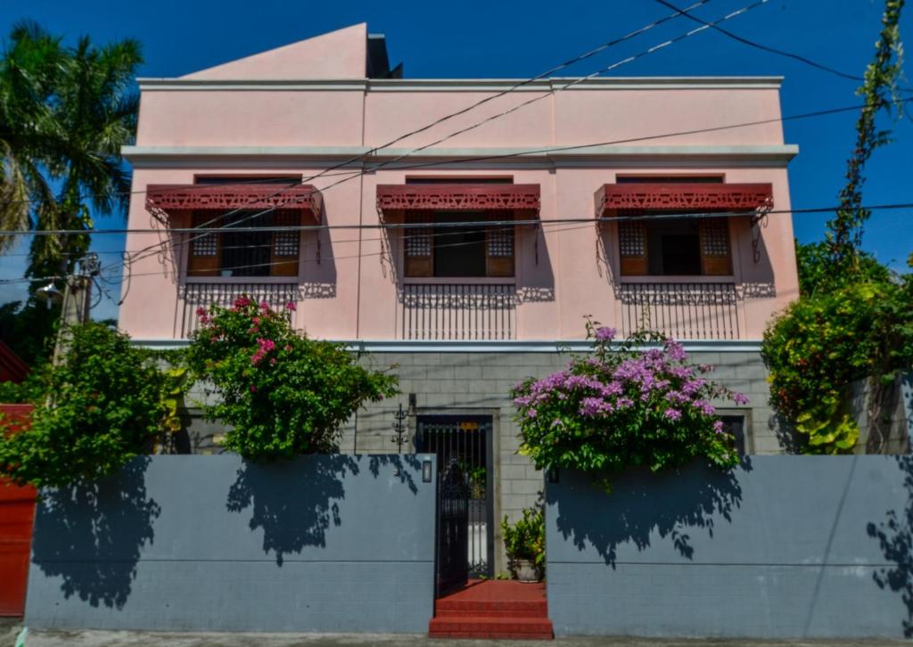 una casa rosa con flores delante en Casita Aurora Bed and Breakfast en Legazpi