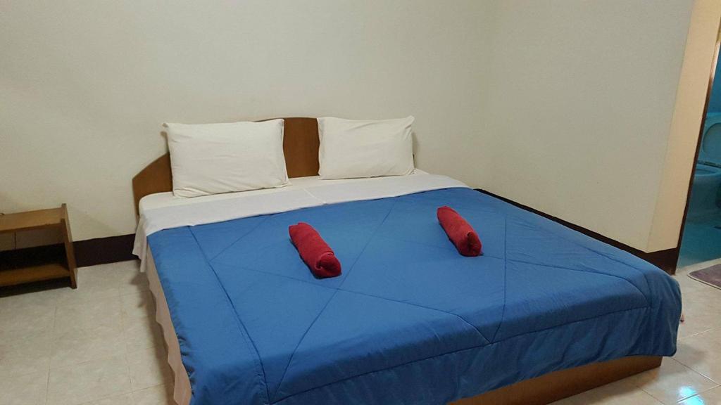 a blue bed with two red pillows on it at LP Apartment in Sakon Nakhon