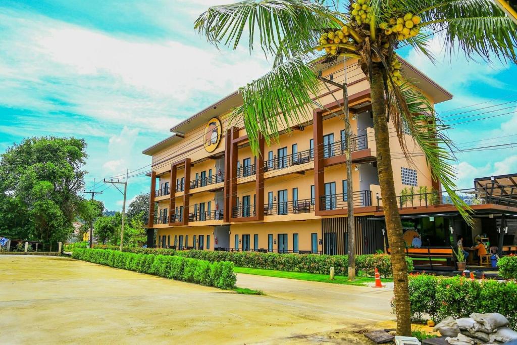 a building with a palm tree in front of it at The Ele Hotel Ranong - SHA Extra Plus in Ranong