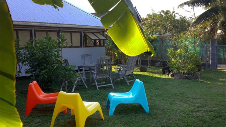 quattro sedie di plastica sedute nell'erba in un cortile di JUSTMOOREA Location Haapiti a Haapiti
