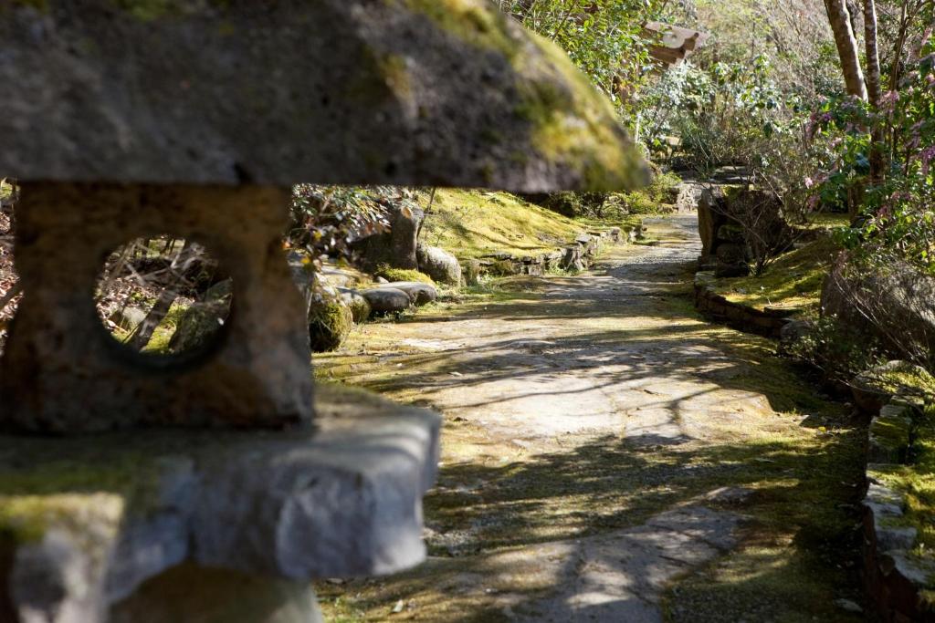 un camino de piedra en un jardín con árboles y césped en Kotohira Guest House en, en Hita