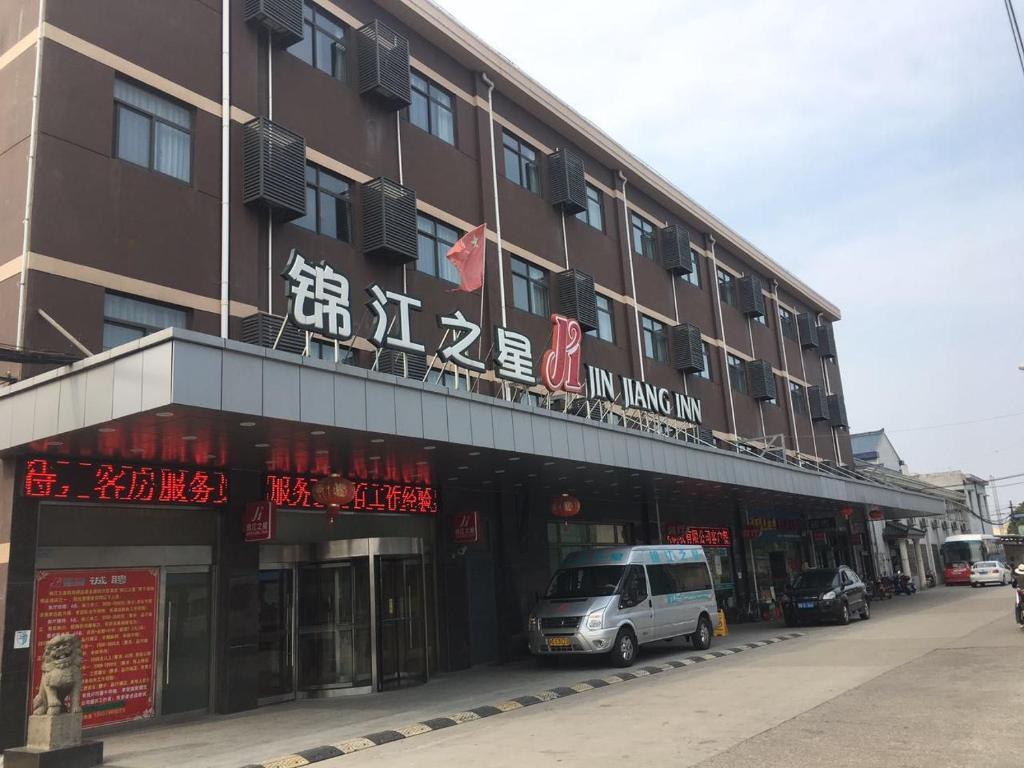um edifício com uma carrinha estacionada em frente em Jinjiang Inn Shanghai Pudong Jichangzhen em Xangai