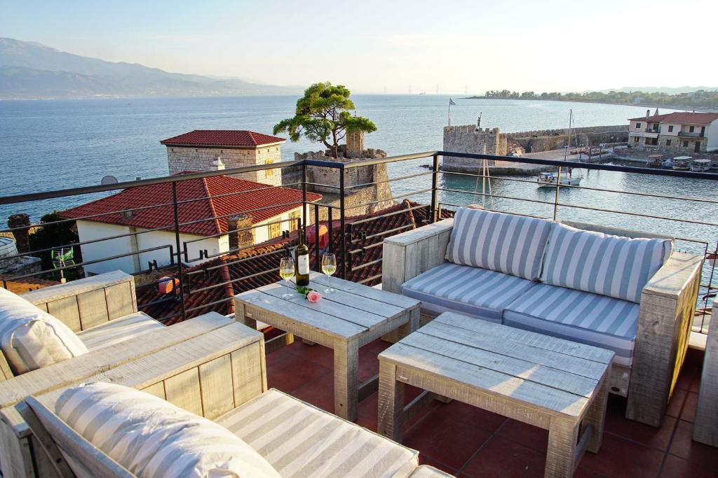 un balcón con sofás, mesas y agua en PEPO'S GUESTHOUSE en Nafpaktos