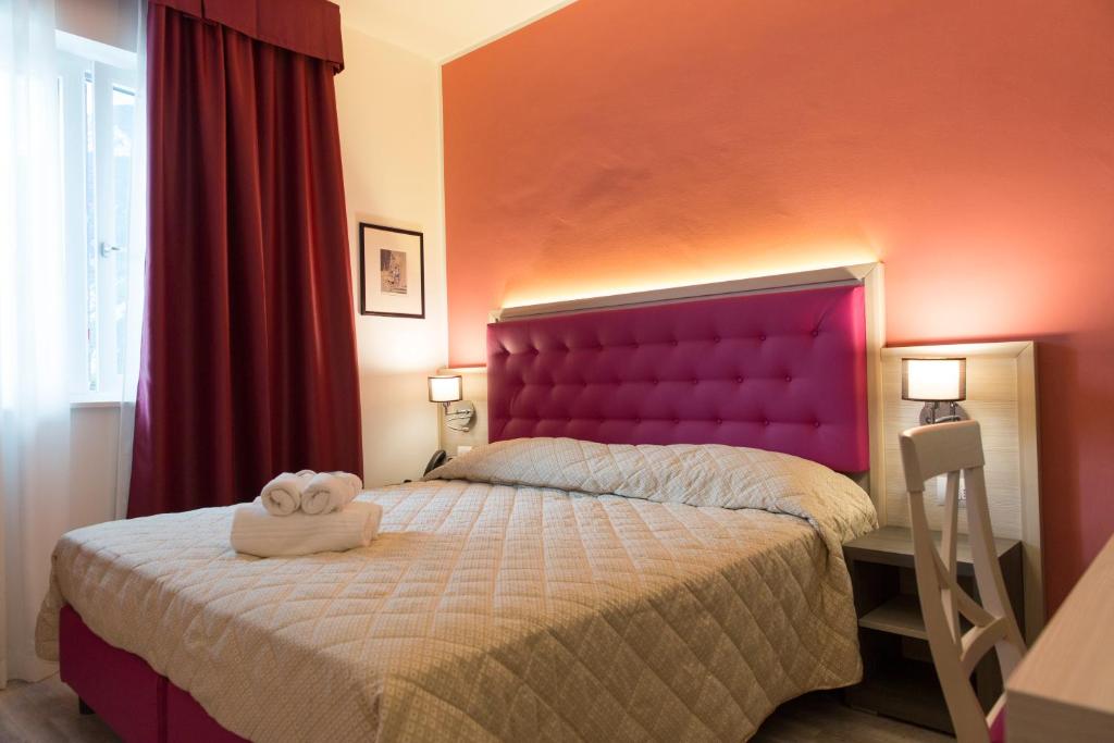a bedroom with a large bed with a purple headboard at Alma Living Hotel- Al Girarrosto in Venzone