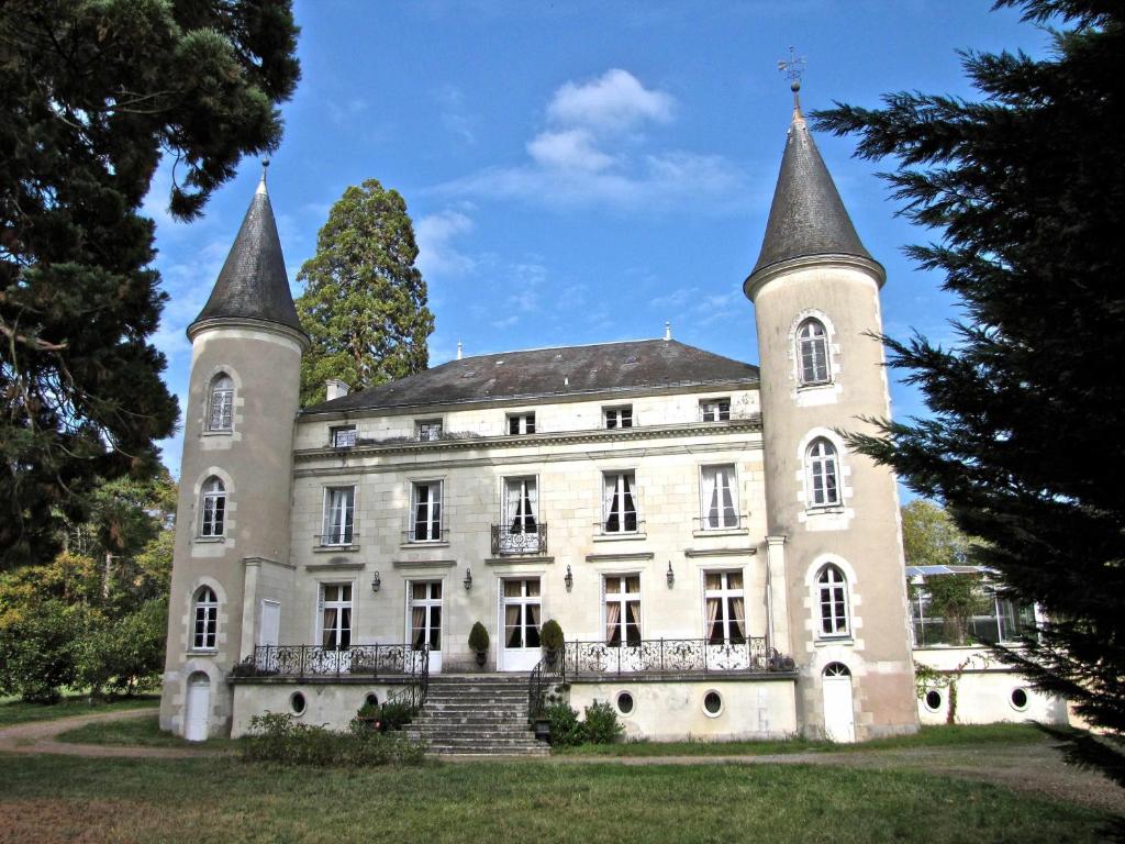 an old castle with two towers on a grass field at Château Les Vallées in Tournon-Saint-Pierre