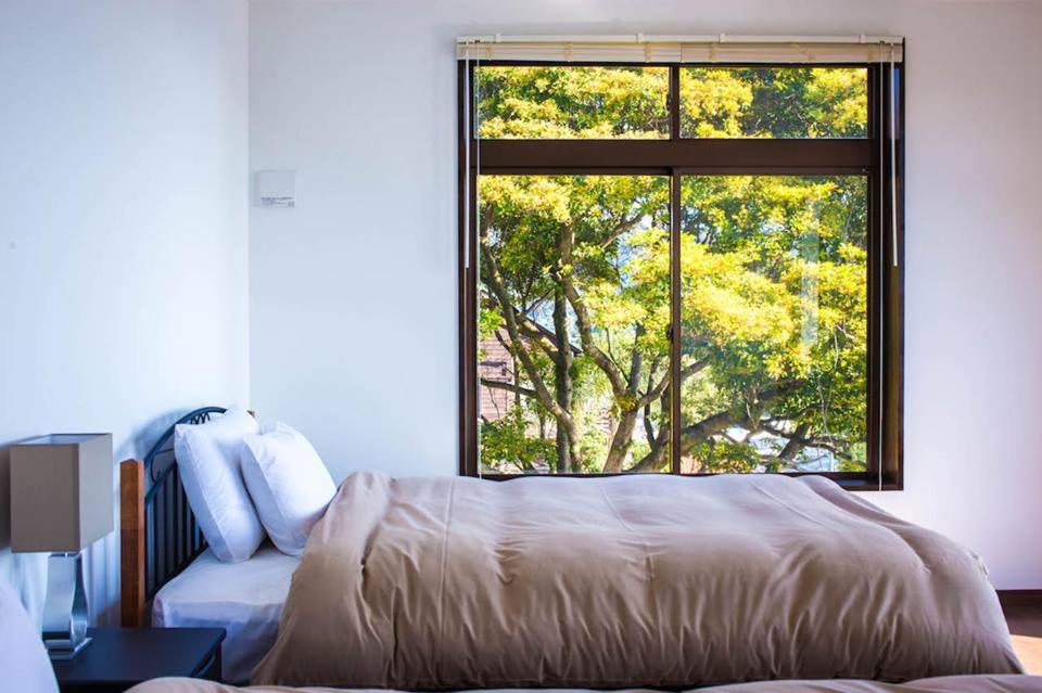 - une chambre avec un lit et une grande fenêtre dans l'établissement The Little Garden, à Miyazaki