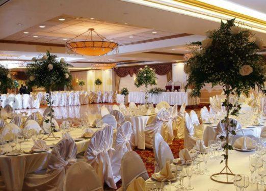 a banquet hall with white tables and white chairs at The Royal Regency Hotel in Yonkers
