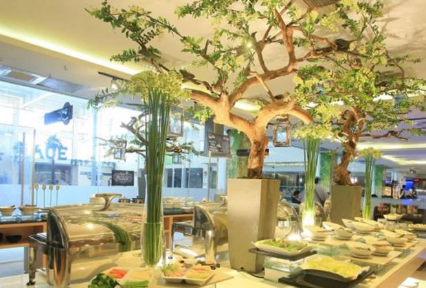 a restaurant with trees and plates of food on a table at ACE Hotel and Suites in Manila