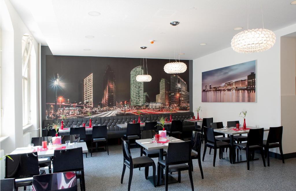 a dining room with tables and chairs and a painting of a city at Jugendherberge Berlin Ostkreuz in Berlin