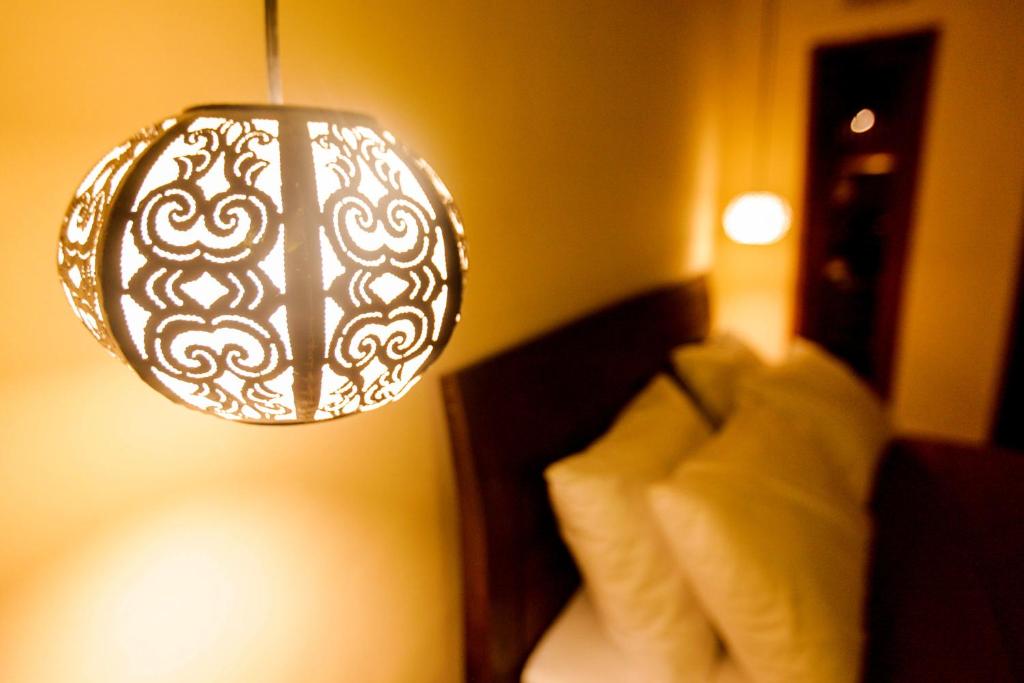 a lamp hanging over a bed in a room at Arsuma Guest House in Gianyar