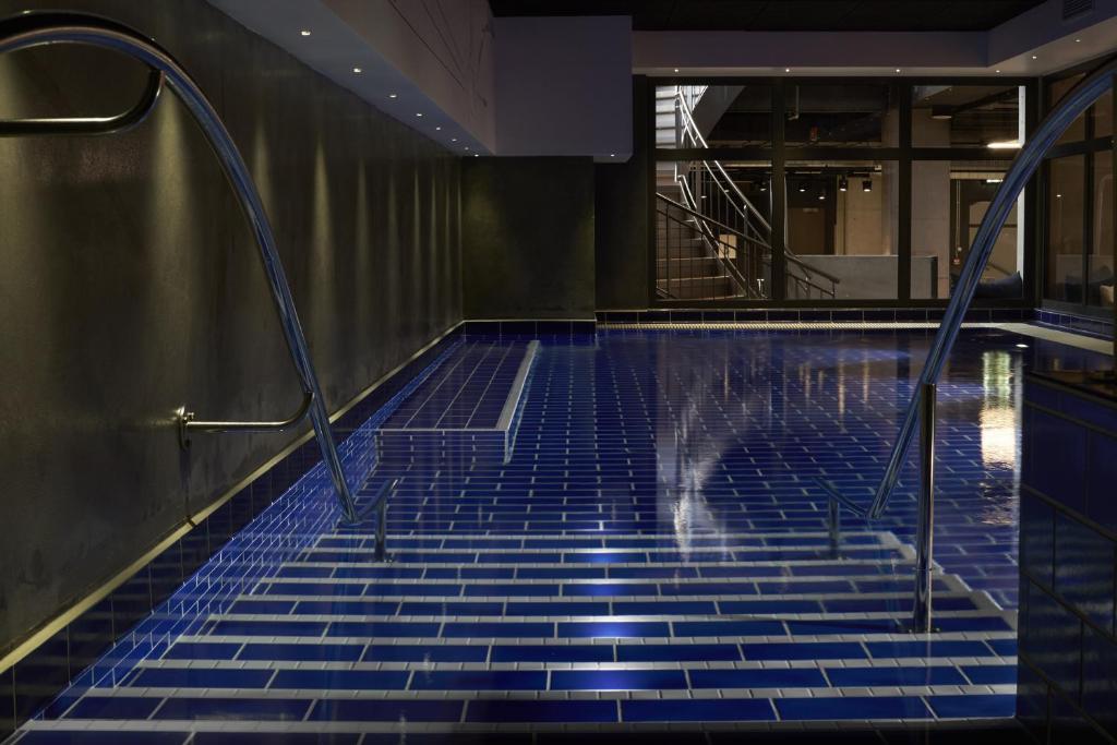 a swimming pool with blue tiles on the floor and stairs at Steel House Copenhagen in Copenhagen
