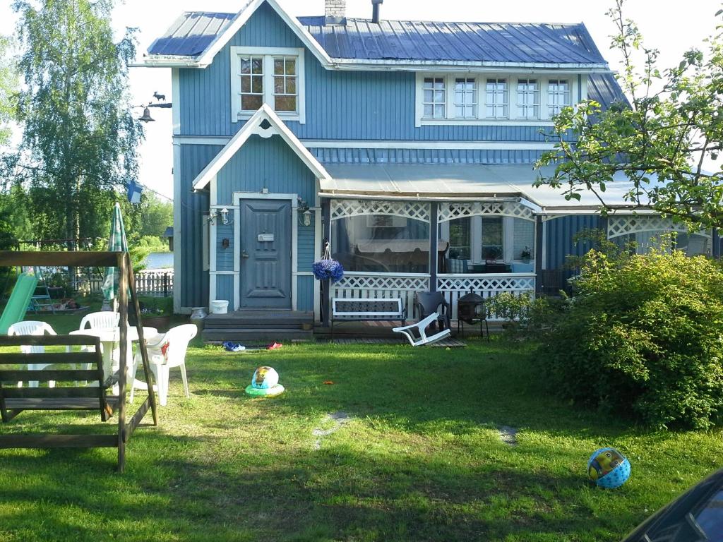 uma casa azul com um quintal com um parque infantil em Paratiisi Villat em Gäddnäs