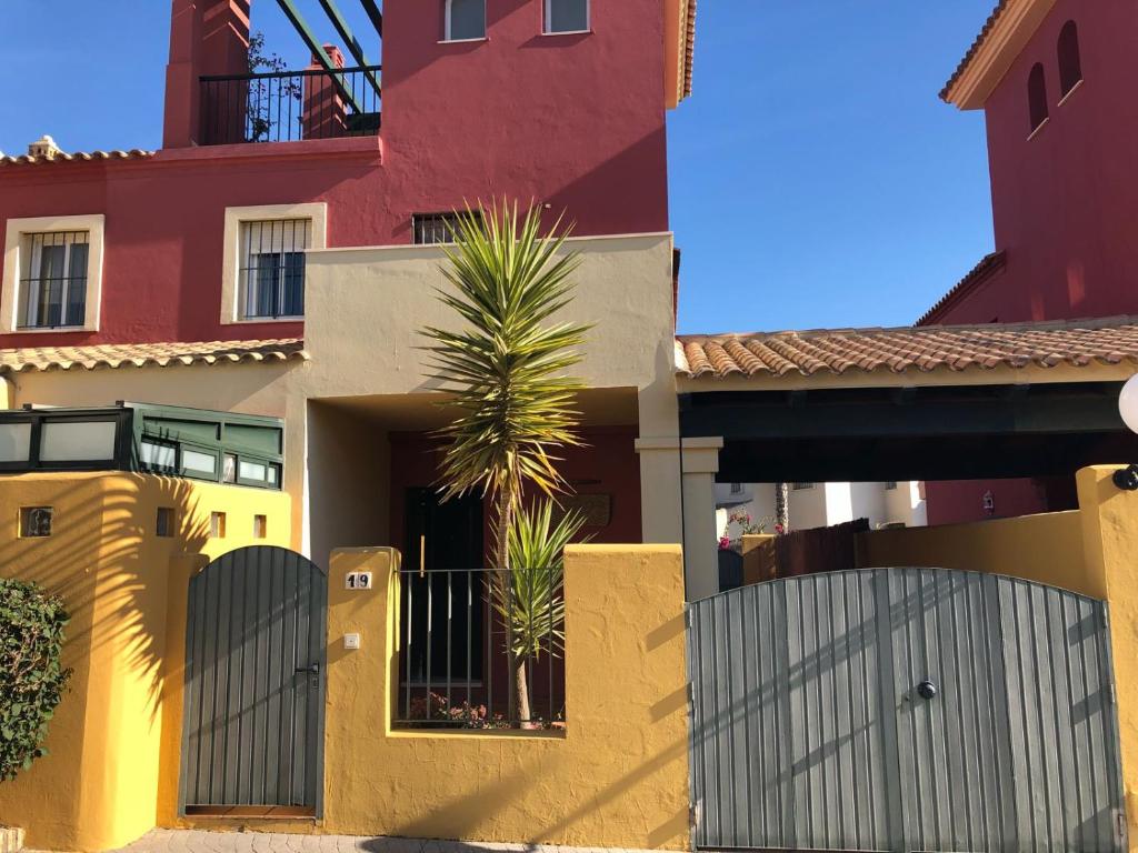 a house with a fence and a palm tree at Residencial Las Redes - 19 in El Puerto de Santa María