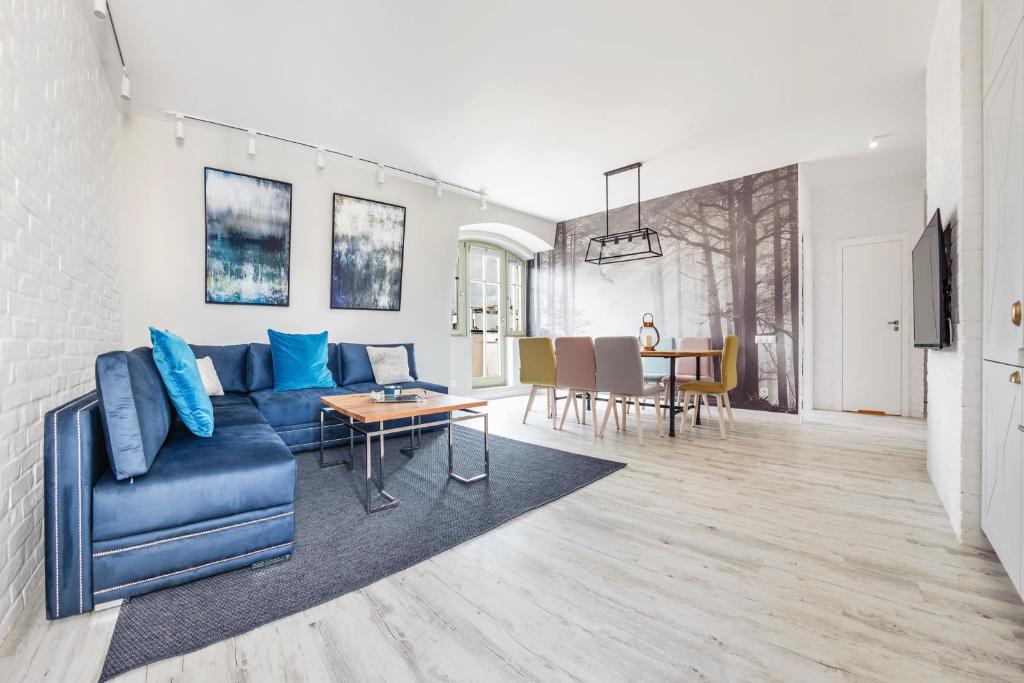 een woonkamer met een blauwe bank en een tafel bij Apartamenty Sun & Snow Na Monte Cassino in Sopot